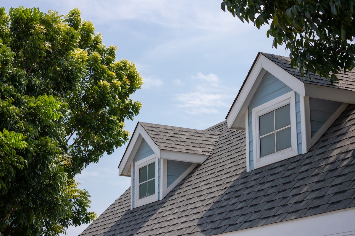 Roof shingles with garret house with dark asphalt tiles on the roof